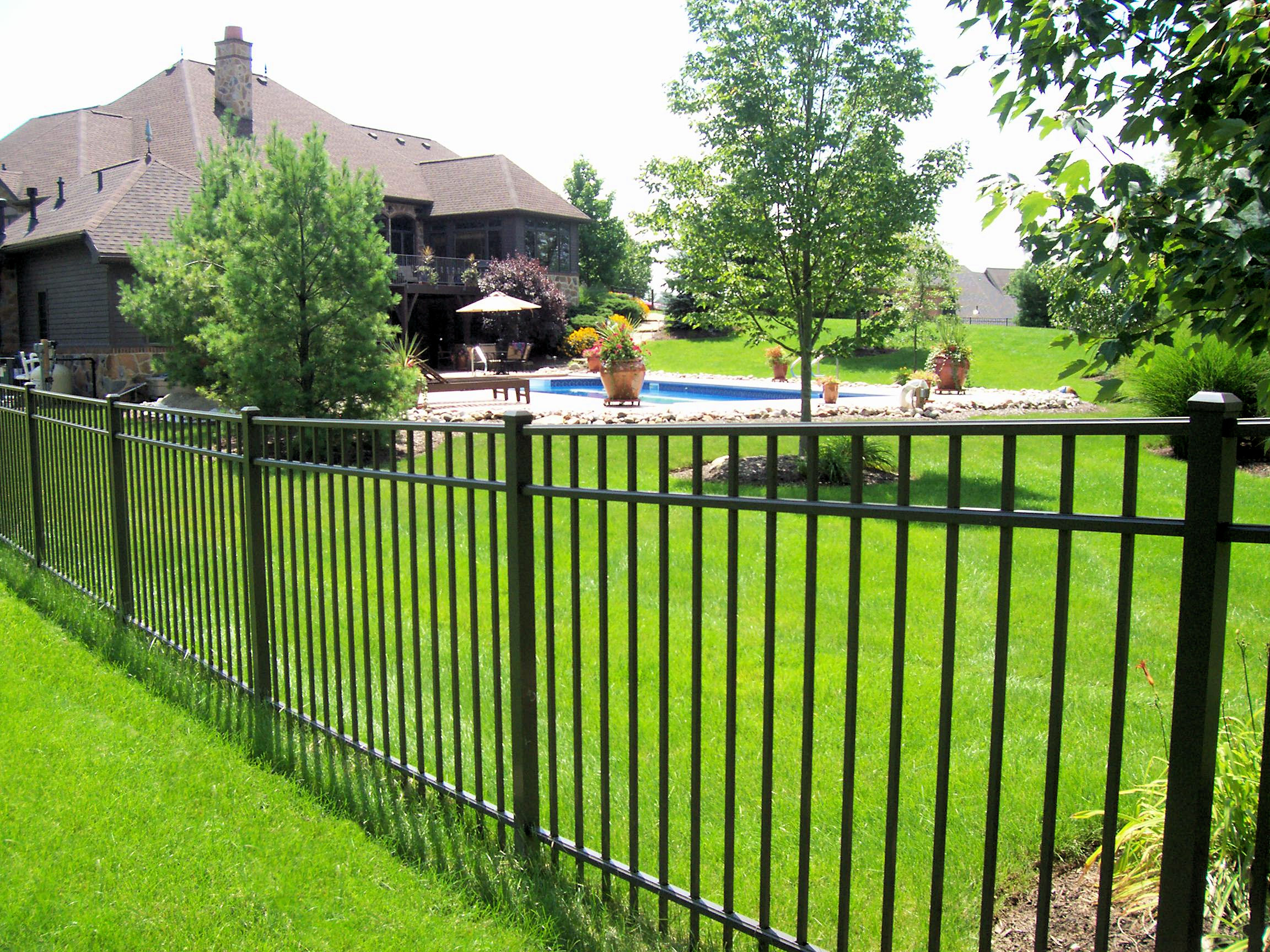 A fence that is in the grass near some trees.